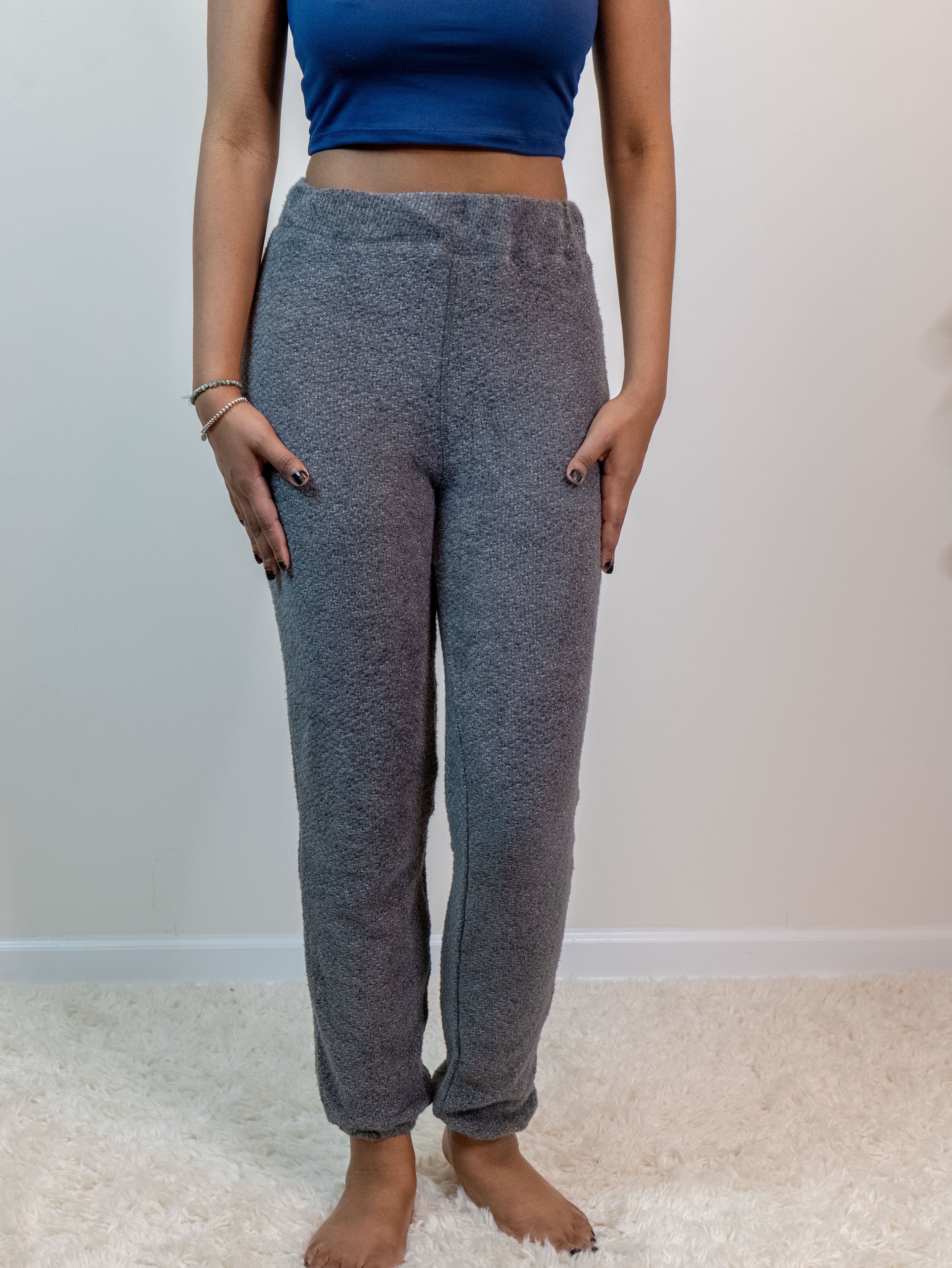 Charcoal-colored fuzzy lounge pants with an elastic waistband and ankle cuffs, made from a soft 60% polyester, 40% nylon blend for ultimate comfort. Model is 5'4" wearing a small