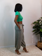 Model showing side of jogger, hand in the pocket, wearing a green crop top