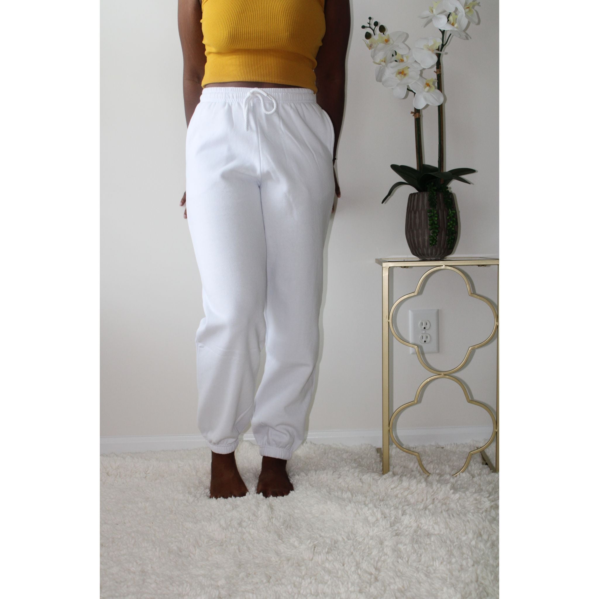 White sweatpants with side pockets, made from 60% cotton and 40% polyester, featuring a 2-inch elastic waistband and elastic cuffs at the ankles for a comfortable, casual style. Model is 5'4" wearing a small. Front view