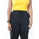 Black sweatpants with side pockets, 2-inch elastic waistband, and elastic cuffs at the ankles, made from 60% cotton and 40% polyester for a comfortable, casual style. Model is 5'4" wearing a small. Close up front