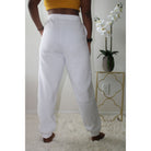 White sweatpants with side pockets, made from 60% cotton and 40% polyester, featuring a 2-inch elastic waistband and elastic cuffs at the ankles for a comfortable, casual style. Model is 5'4" wearing a small. Back view